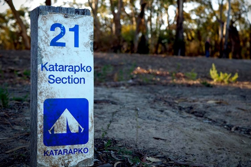A small blue and white campsite post adorned with a sign that features a tent icon and writing that reads 21 Katarapko Section
