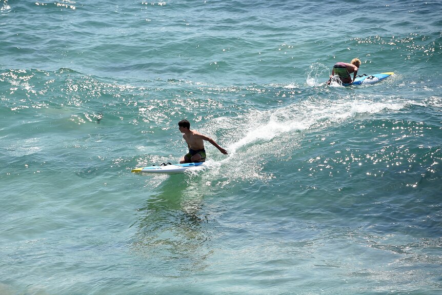 two young boys riding surf board in the ocean