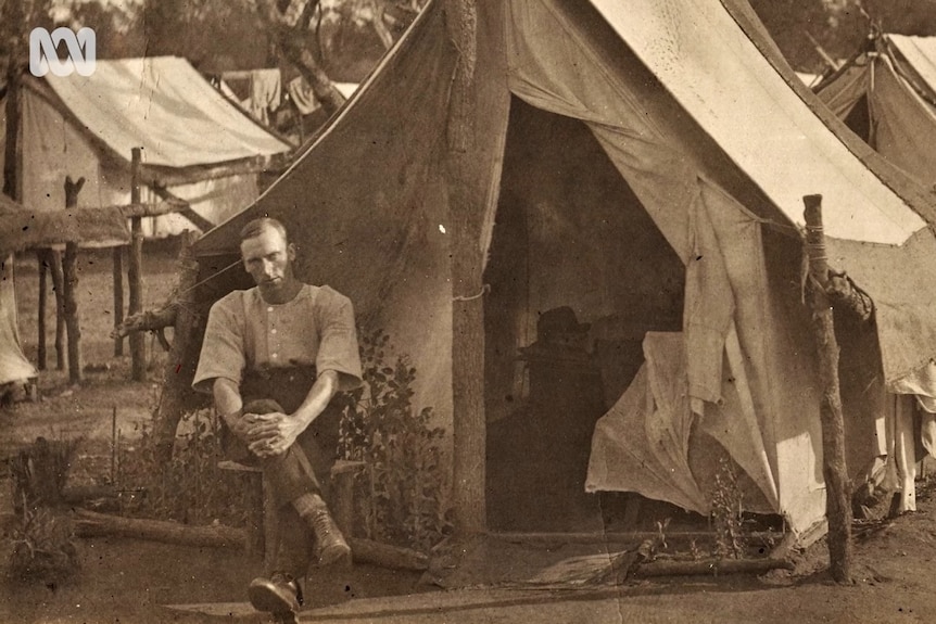 A returned WWI soldier sitting in front of a tent.