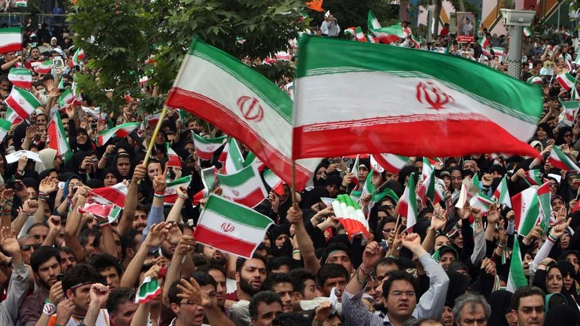 Supporters of Iranian President Mahmoud Ahmadinejad wave national flags during an election rally.