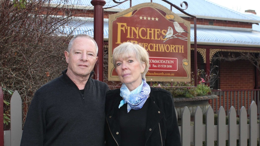 A couple stand outside of the gate of their Bed and Breakfast.