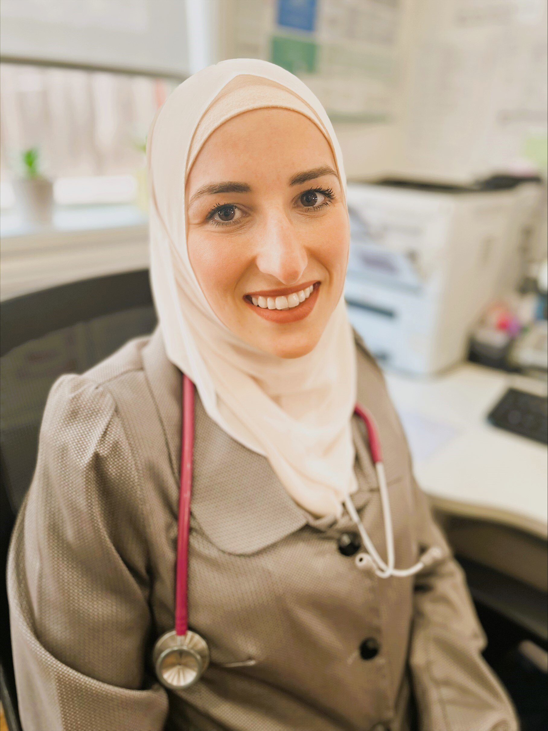 A photo of Dr Amireh at her desk. She's wearing a cream coloured hijab.