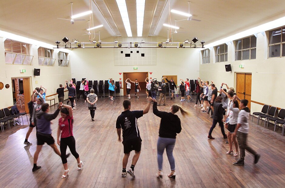Wide shot of a group of dance partners learning dance steps.