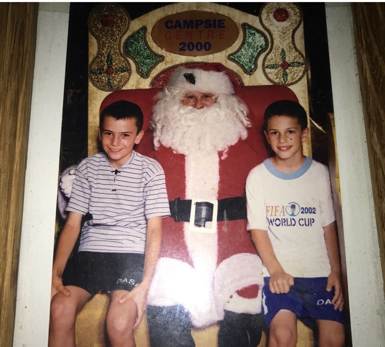 Two young boys pose for a photo with a shopping centre Santa Claus 