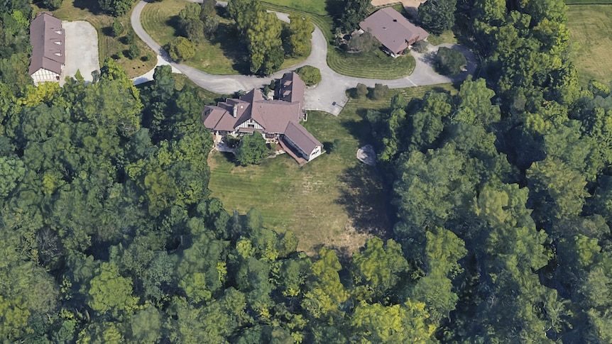 A satellite google maps photo of a large house at the edge of forest 