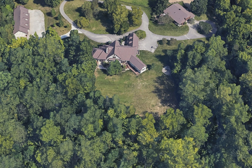 A satellite google maps photo of a large house at the edge of forest 