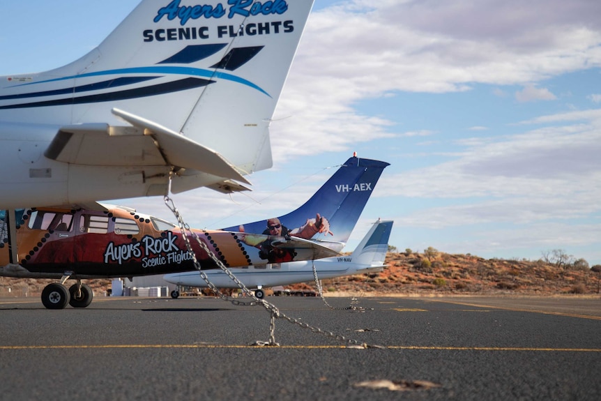 Small aircraft used for scenic flights are chained to the airport tarmac