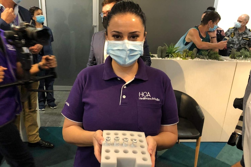 A woman holds a tray of liquid vials