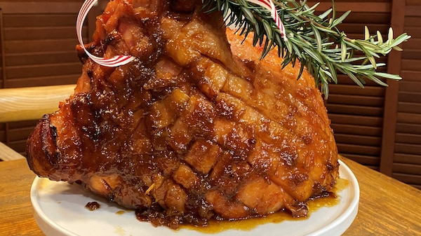 A glazed Christmas ham sitting on a cake stand.