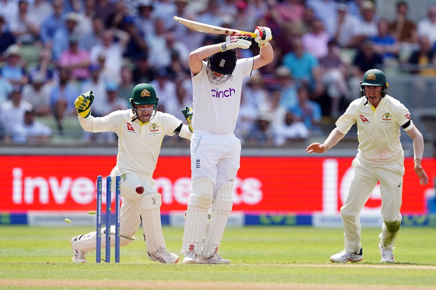 Harry Brook holds his bat aloft as the ball hits the stumps, while Alex Carey and Marnus Labuschagne celebrate