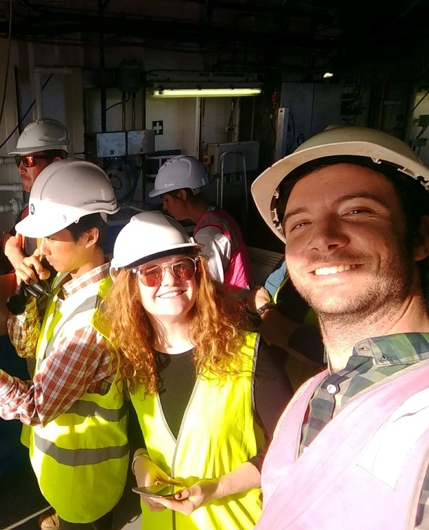 A group of scientists with helmets on, on board a research boat.