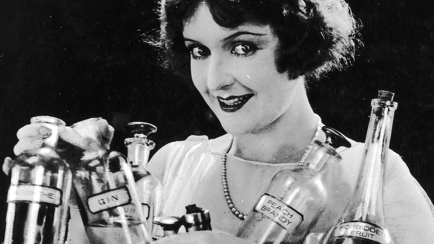 1925 photo of smiling woman holding bottles