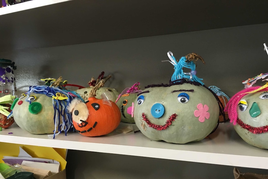 Pumpkins in a row with faces formed by buttons and wool.