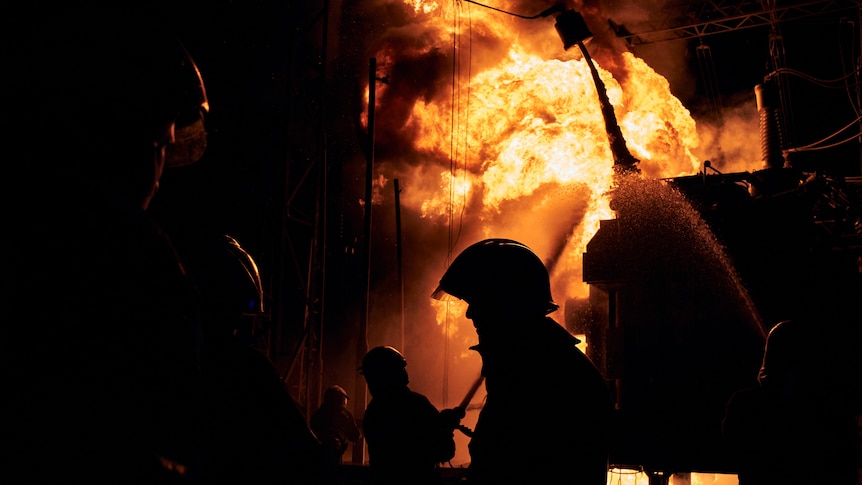 a firefighter silhouetted against a huge blaze