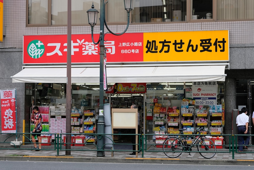 Pharmacy storefront with large red and yellow sign. 