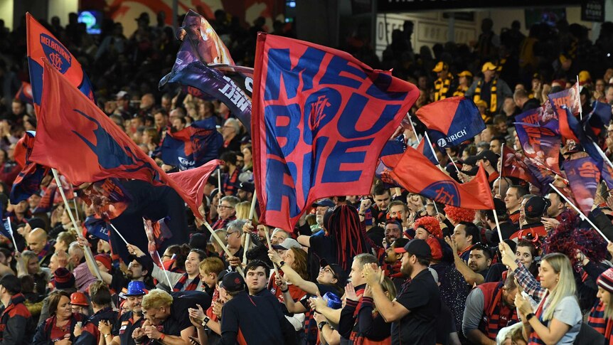 Supporters in a grandstand wave red and navy banners