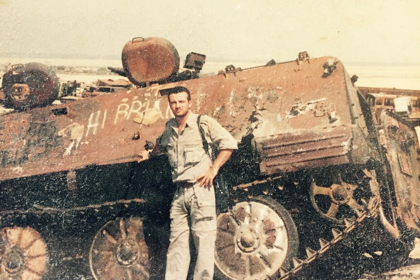 Young navy officer standing in front of a tank. 