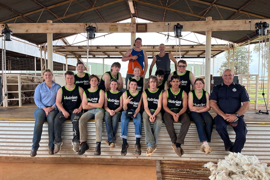 a group of men and women sit in a shearing shed