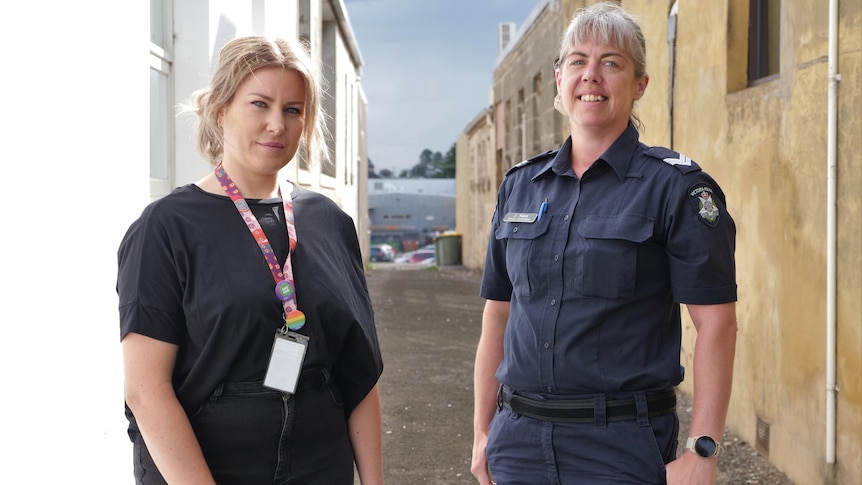 A police officer and female youth worker stand posed in alleyway 