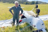 Man stands beside upturned plane