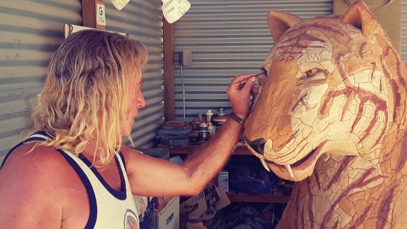 A man sculpts a massive statue of a tiger