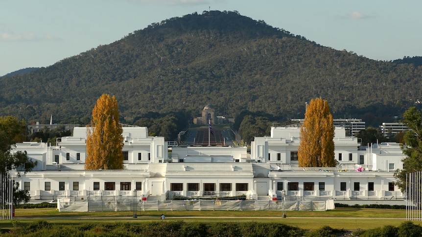 Distance view from the front, emphasising symmetry. White building, green surrounds