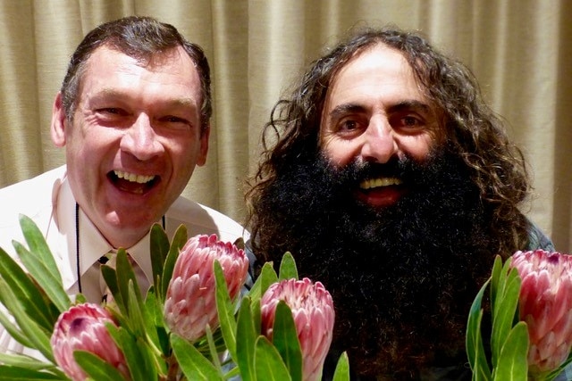 Two smiling men, one with a massive dark beard