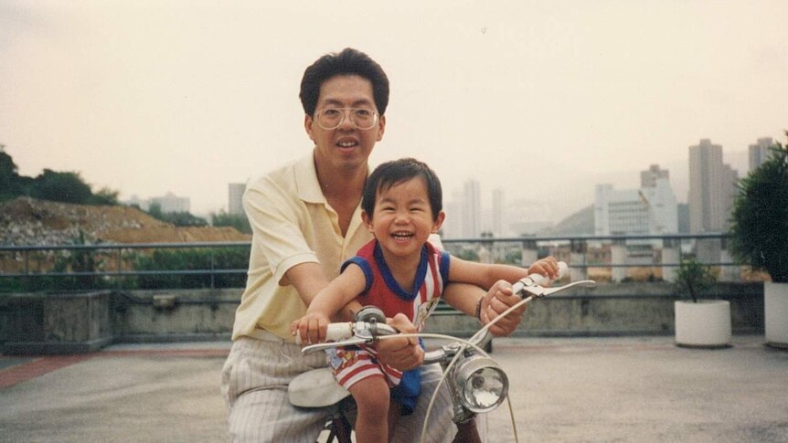 An old photo of Curtis Cheng holding his son Alpha Cheng on a bicycle.