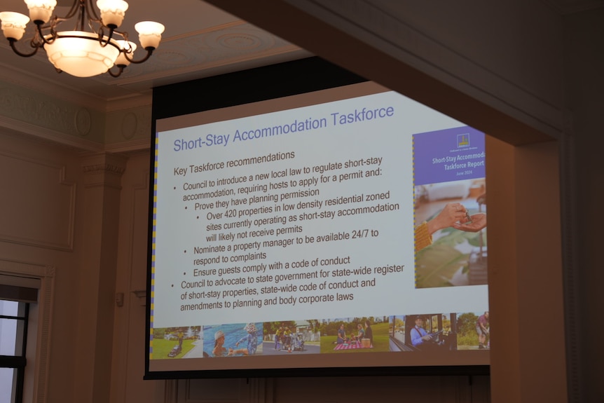 A projector shows a council-branded slide about short stay accommodation.
