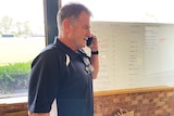 A man in a polo shirt answers a mobile phone