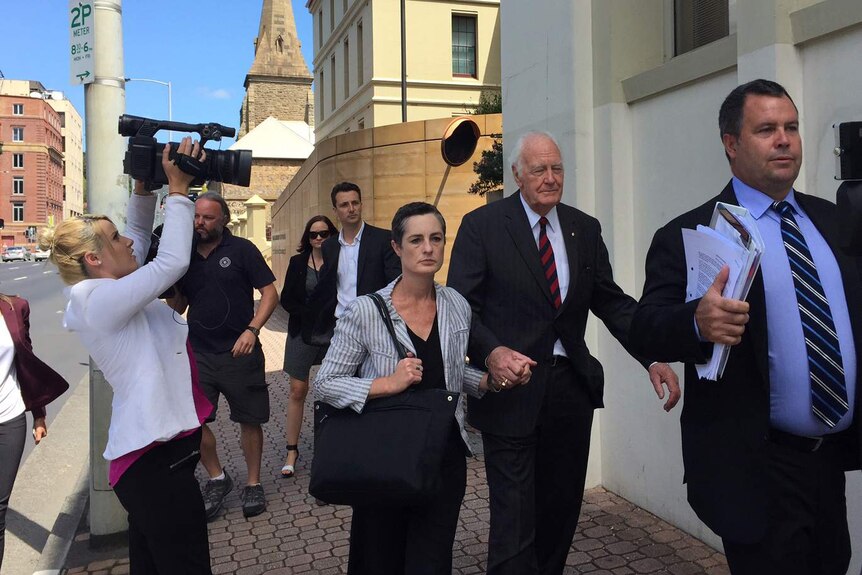 Peter Hollingworth leaves the commission with daughter and legal counsel, followed by media.