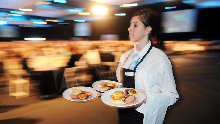 A waitress carrying three plates of breakfast food.