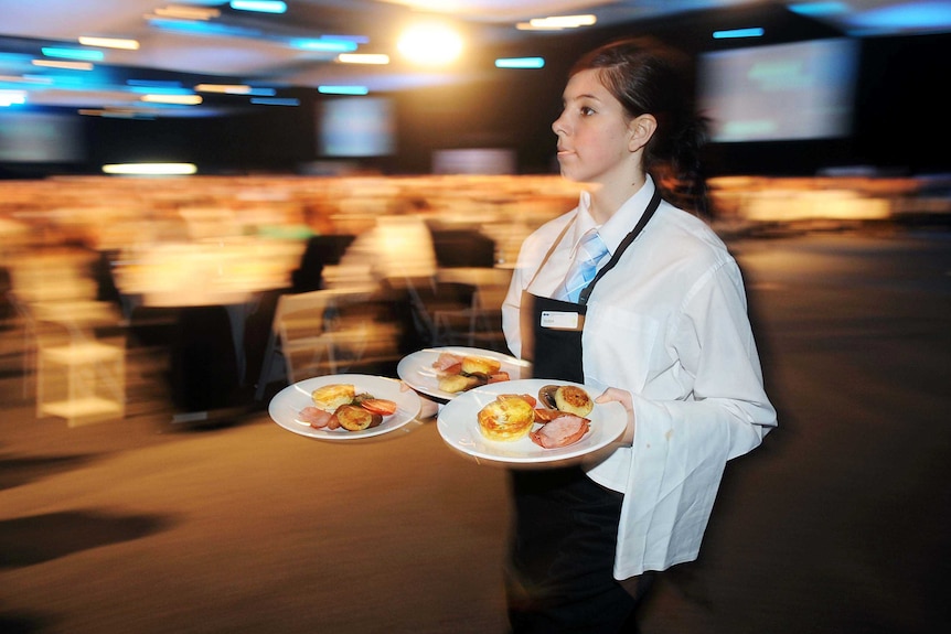 A waitress carries food in a conference hall