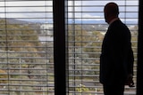 Mike Burgess looks out heavily blinded windows to Parliament House.