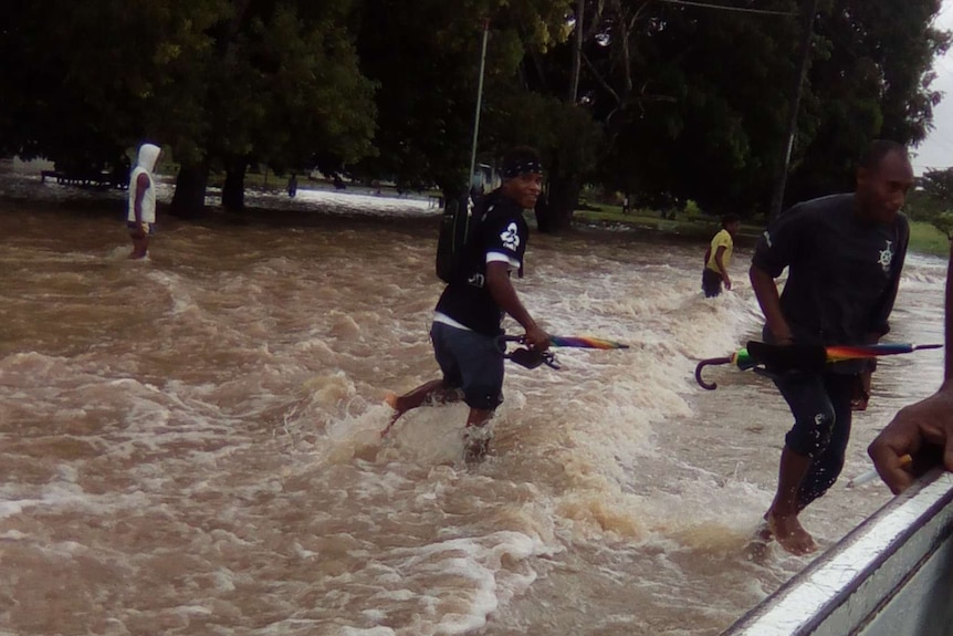 Men run in storm waters next to a boat