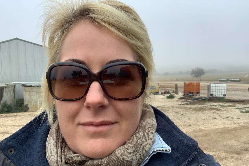 Lucy wearing sunglasses, standing on her and her husband's farm in country WA.