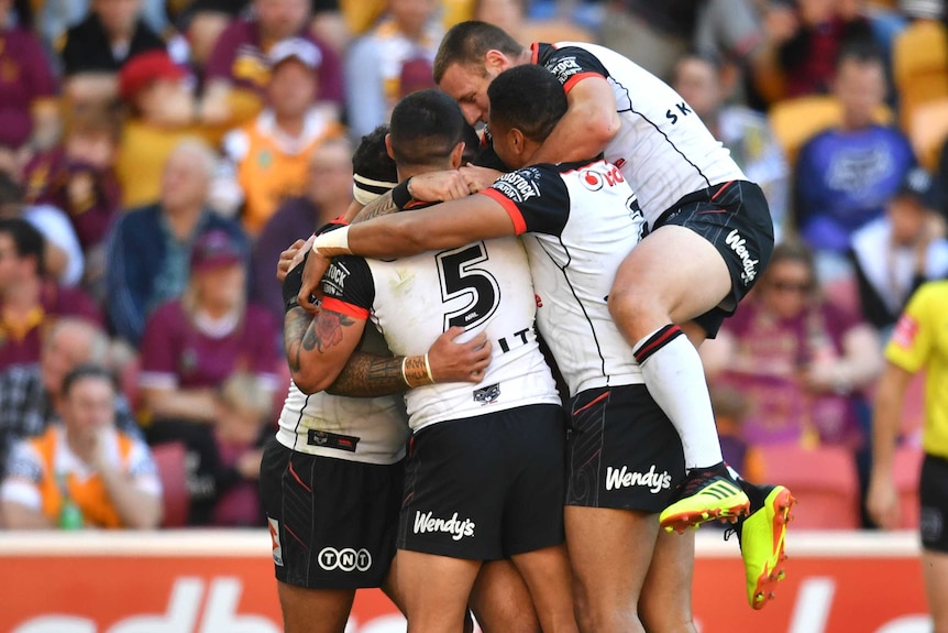The Warriors celebrate a try against the Broncos.