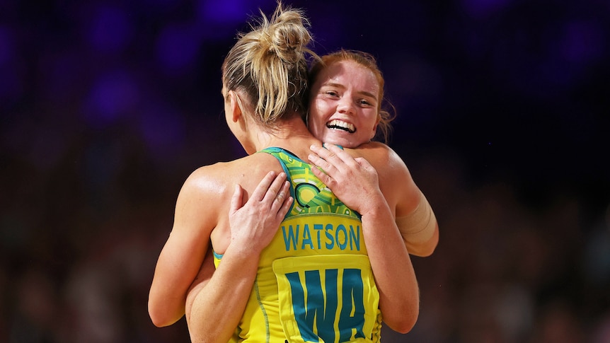 Two Australian netball players embrace after beating England at the Commonwealth Games.