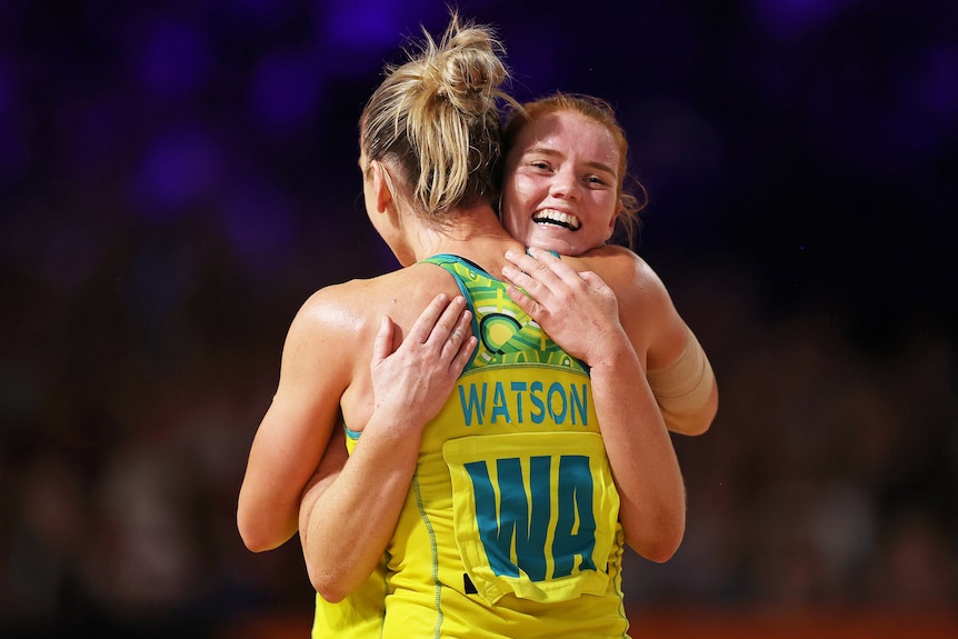 Two Australian netball players embrace after beating England at the Commonwealth Games.