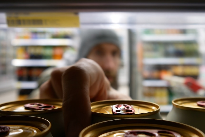 Man reaches for cans of drink in the fridge