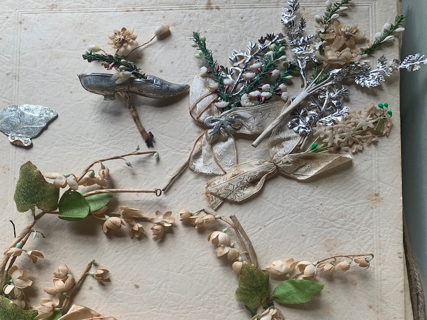 A vintage bride's headpiece and dried flowers rest on a yellowing paper.