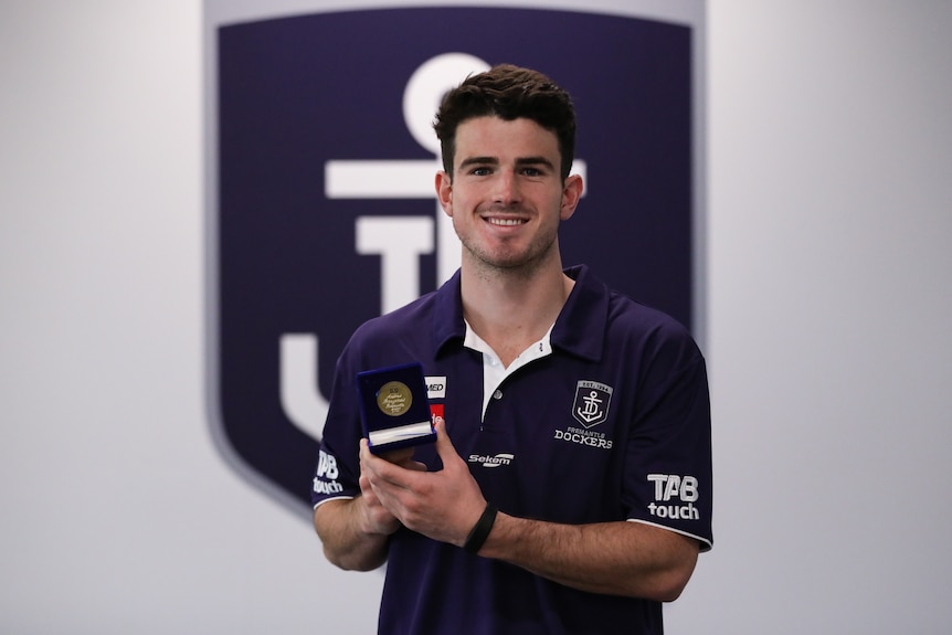 Le joueur des Dockers de Fremantle, Andrew Brayshaw, tient sa médaille Geoff Christian devant une bannière des Dockers