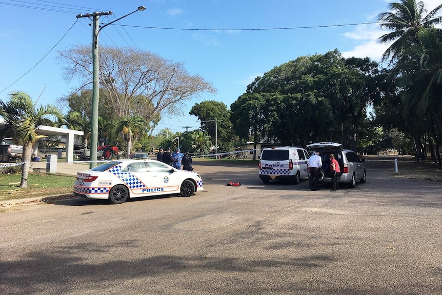 Police officers and cars cordon off a street where they are investigating the suspicious deaths of two men.