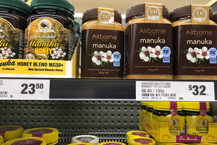 square jars with rounded edges sit on a shelf, full on honey