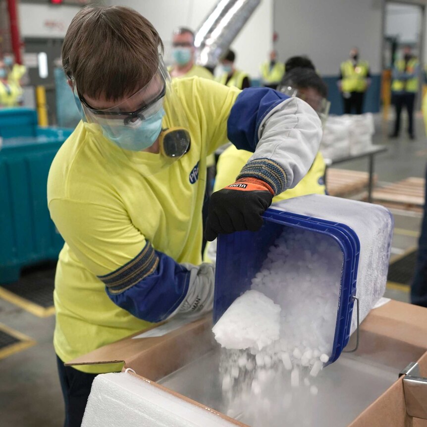 A worker empties dry ice from an esky into a container.