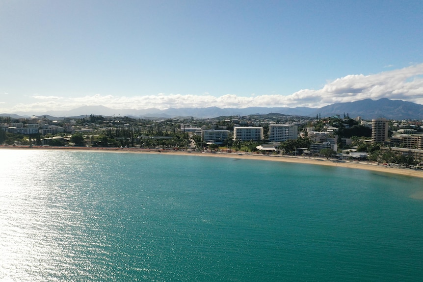 An aerial view showing teal water and hotel buildings near Anse Vata beach in New Caledonia. 