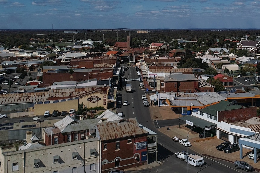 A drone shot showing the town, blue skies, a large church and silos can be seen in the distance.