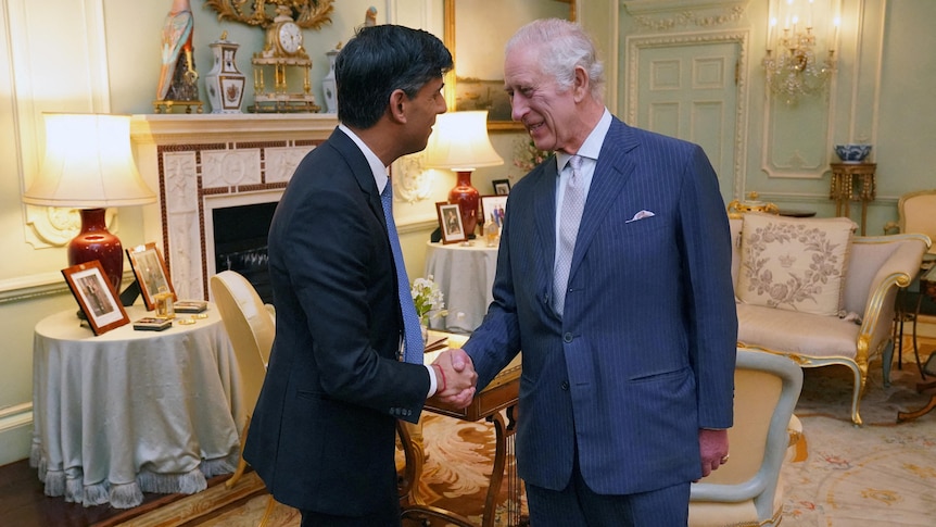 King Charles shakes hands with UK PM. The king is smilling at him.