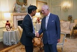 King Charles shakes hands with UK PM. The king is smilling at him.