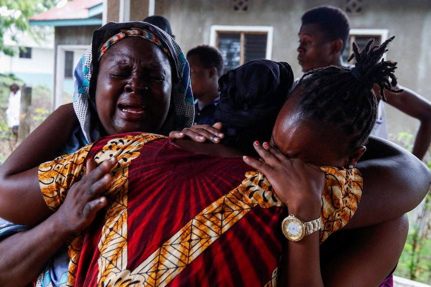 Relatives of followers of a Christian cult cry and hug in mourning for their loved ones.
